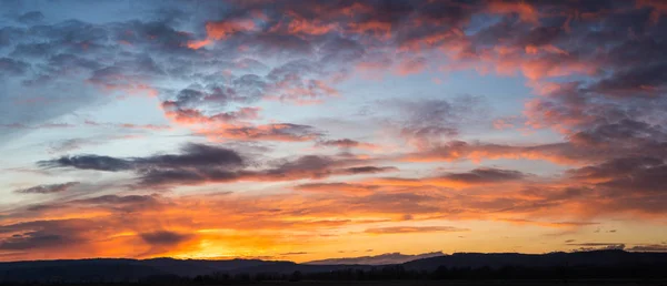 Natural Sunset Sunrise Over Field Or Meadow. Bright Dramatic Sky And Dark Ground. Countryside Landscape Under Scenic Colorful Sky At Sunset Dawn Sunrise. Sun Over Skyline, Horizon. Warm Colours.