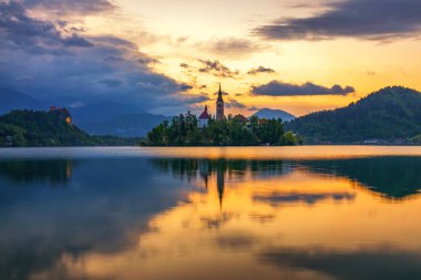Bled Gölü 'nde dramatik bir gün doğumu, Bled Gölü' nde gündoğumu manzarası, Maria ve Kale 'nin dağlık alanda hac kilisesi (Stol, Vrtaca, Begunjscica). Kan, Slovenya,
