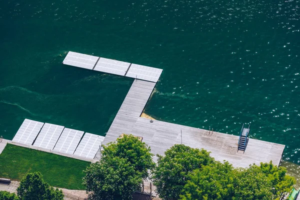 Empty wooden pier close to Bled lake, swimming area of the Bled lake under the sunny sky. Platform beside lake. Wooden pier on the lake. Bled, Slovenia