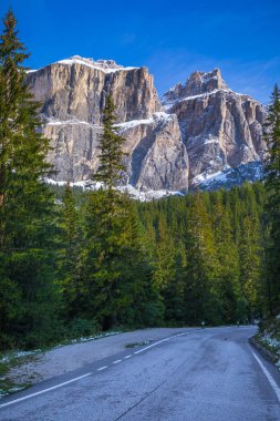 Dolomit İtalya Alpleri'nde. Güzel bir gün. Kalker ve dolomit kayaları dibinde iğne yapraklı ormanlarda yol geçmektedir. Aktif ve araba turizm kavramı
