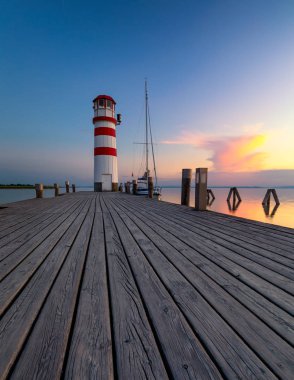 Neusiedl Gölü 'ndeki deniz feneri, Podersdorf am See, Burgenland, Avusturya. Avusturya 'da gün batımında deniz feneri. Podersdorf 'ta deniz feneri olan ahşap iskele Avusturya' da Neusiedl Gölü üzerinde.