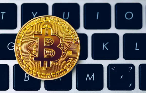 Bitcoin on compuer keyboard in background, symbol of electronic virtual money and mining cryptocurrency concept. Coin crypto currency bitcoin lies on the keyboard. Bitcoin on keyboard.