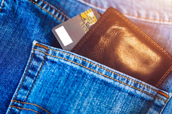 Credit card in wallet in pocket of jeans, closeup. Closeup of wallet and credit card in jeans trousers pocket.