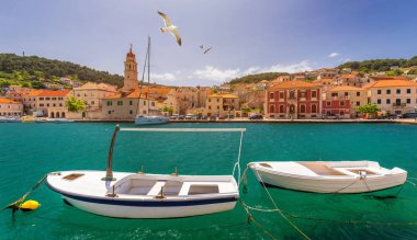 Panorama of picturesque town Pucisca in Croatia, Island Brac, Europe. Pucisca town mediterranean panorama with seagull's flying over the town. Croatia, Island Brac, Europe. clipart