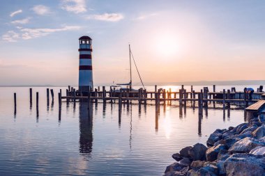Neusiedl Gölü 'ndeki deniz feneri, Podersdorf am See, Burgenland, Avusturya. Avusturya 'da gün batımında deniz feneri. Podersdorf 'ta deniz feneri olan ahşap iskele Avusturya' da Neusiedl Gölü üzerinde.