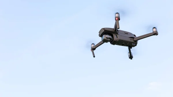 Drone flying over landscape. UAV drone copter flying with digital camera. Drone flying overhead in cloudy blue sky. Quad copter is flying over the  field.