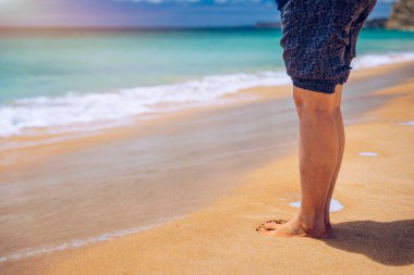 Sahilde yalınayak yürüyen bir kadın. Genç bayanın bacağını kapat.