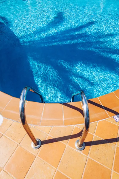 Swimming pool with stair. Grab bars ladder in the blue swimming