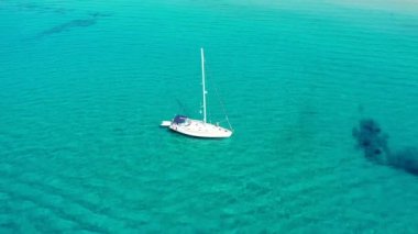 Güneşli bir günde gölde yat. Yelkenli. Deniz yatı, hava fotoğrafçılığı dronu. İnanılmaz bir yat ya da turkuaz ve şeffaf denizi olan bir yelkenli. Mavi göldeki yelkenli teknelerin üst görüntüsü