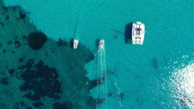 Güneşli bir günde gölde yat. Yelkenli. Deniz yatı, hava fotoğrafçılığı dronu. İnanılmaz bir yat ya da turkuaz ve şeffaf denizi olan bir yelkenli. Mavi göldeki yelkenli teknelerin üst görüntüsü