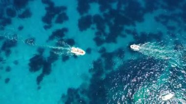 Güneşli bir günde gölde yat. Yelkenli. Deniz yatı, hava fotoğrafçılığı dronu. İnanılmaz bir yat ya da turkuaz ve şeffaf denizi olan bir yelkenli. Mavi göldeki yelkenli teknelerin üst görüntüsü