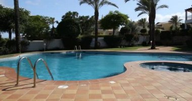 Güneşli bir günde yüzme havuzu, dinlenme yerleri ve palmiye ağaçları, tatil için cennet. Bahçesi palmiye ağaçları ve çiçeklerle dolu arka bahçe yüzme havuzu. Yüzme havuzlu arka bahçe..