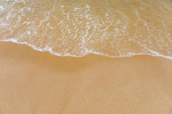 Blue ocean wave on sandy beach. Soft wave of blue ocean on sandy beach. Background. Top view of Beautiful beach with tranquil wave, sea and ocean background, summer vacation concept. 