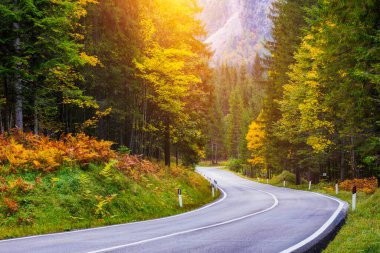 Dağ yolu. Kayalıklı manzara, bulutlu güneşli gökyüzü ve yazın akşamları güzel asfalt yollar. Klasik tonlama. Seyahat geçmişi. Dağlarda otoyol.  