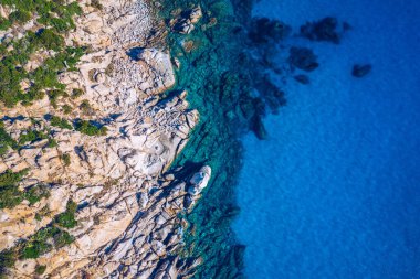 Granit kayalık Akdeniz kıyı şeridi üzerinde açık mavi deniz suyu üzerinde hava fotoğrafı. Okyanus dalgalarının güzel cennet rüyalarının kayalık sahil şeridine çarptığı hava fotoğrafı. Sardunya, İtalya.