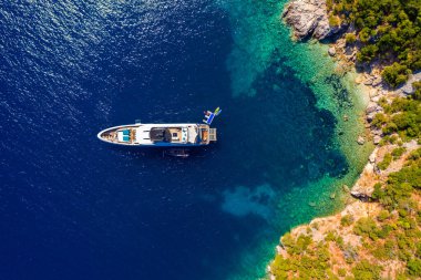 Zümrüt denizdeki demirli yelkenli yatının havadan görünüşü. Bir teknenin havadan görünüşü. Açık deniz sporları, yat. Açık denizde demirleyen yatın havadan görüntüsü. Okyanus ve deniz yolculuğu ve ulaşım