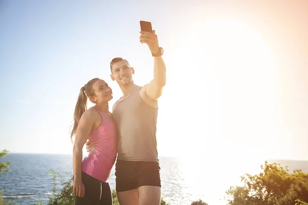 A sports couple makes selfy on the beach.