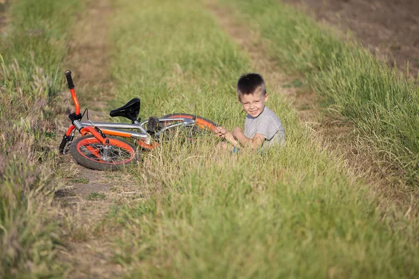 Niño Hermoso Está Sentado Hierba Junto Yace Bicicleta Chico Deportivo — Foto de Stock