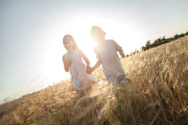 Bir erkek ve bir kız spikelets alanına yürüyor. Çocuk gökyüzüne bak.