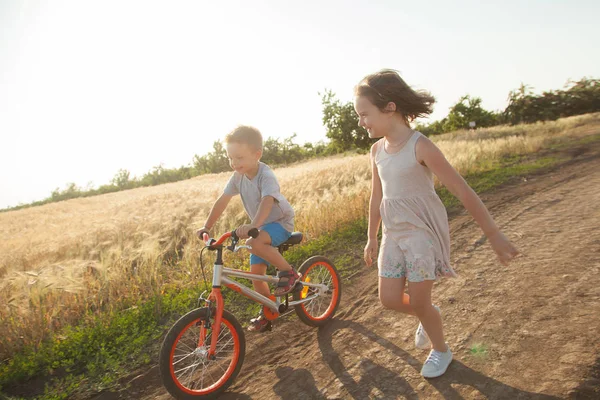 Arkadaşlar çevresindeki kırsal yürüyüş mesafesindedir. Çocuk bir bisiklet sürme ve kız onun yanında yürüyor.