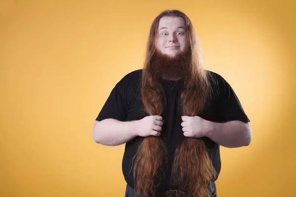 Portrait of a big man on a yellow background. Long red hair and beard.