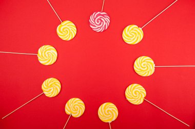 Kırmızı bir arka plan üzerinde tatlı karamel şeker. Parlak lolipop. Pudra sarı ve pembe tatlılar.