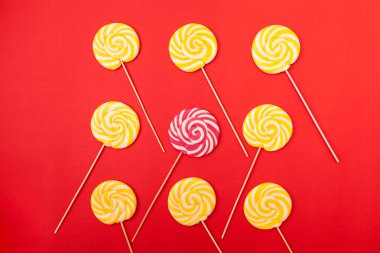Kırmızı bir arka plan üzerinde tatlı karamel şeker. Parlak lolipop. Pudra sarı ve pembe tatlılar.