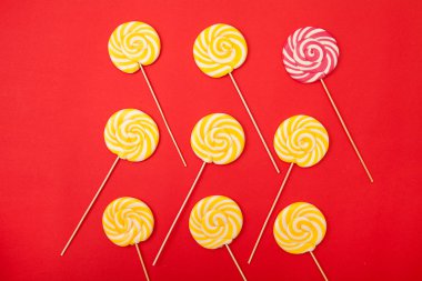 Kırmızı bir arka plan üzerinde tatlı karamel şeker. Parlak lolipop. Pudra sarı ve pembe tatlılar.