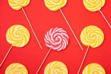 Kırmızı bir arka plan üzerinde tatlı karamel şeker. Parlak lolipop. Pudra sarı ve pembe tatlılar.