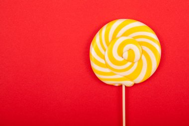 Kırmızı bir arka plan üzerinde beyaz ve sarı lolipop. Tatlı şeker bir sopa. Kutlama arka plan.