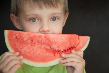 Şirin bebek ve böğürtlen. Yakışıklı bir çocuk karpuz olgun bir dilim tutuyor.