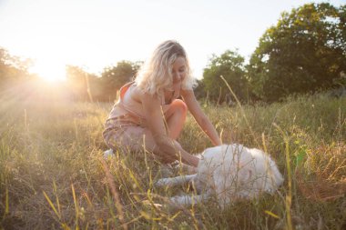 Beyaz bir golden retriever ve beyaz saçlı bir kız parkta yürüyüş.
