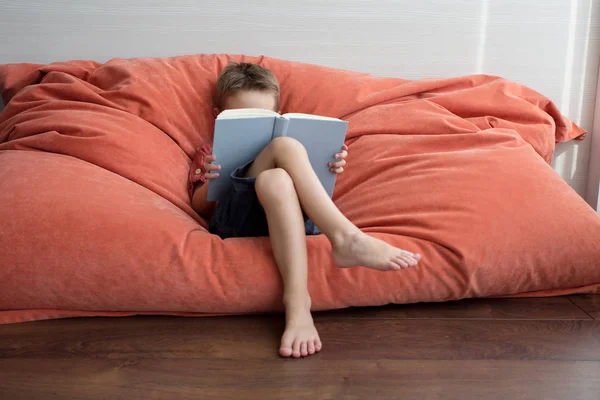 Ein Süßer Junge Liest Ein Buch Auf Der Couch — Stockfoto