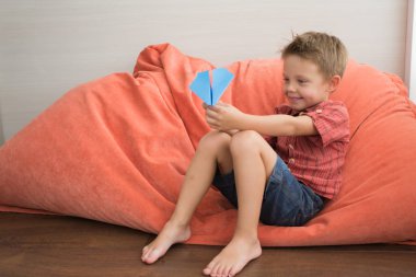 Şirin bir çocuk ve bir kağıt uçak. Çocuk derme çatma bir oyuncakla oynar.