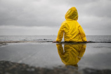 Yağmurlu bulutlar. Çocuk bir sarı yağmurluk içinde.