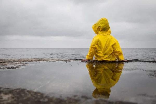 Rainy clouds. Child in a yellow raincoat.