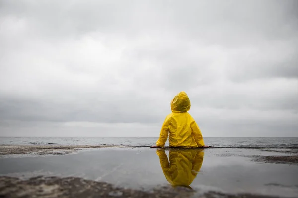 Rainy clouds. Child in a yellow raincoat.