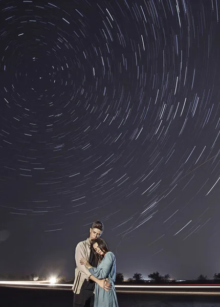 Romantic couple at night under a starry sky.