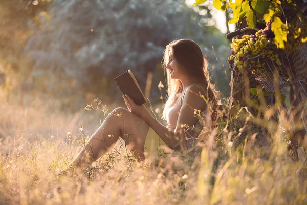 Güzel genç kız öğrenci bir kitap okuma bir ağacın altında bir parkta oturan.