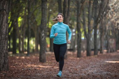 Spor giyim güzel bir kız parkta sonbaharda geziyor.