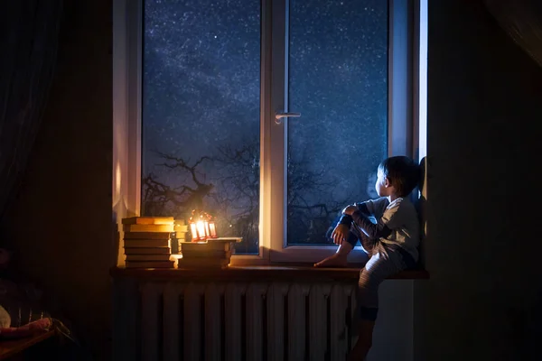 Çocuk gece yıldızlar ve rüyalar pencere kenarında oturur.