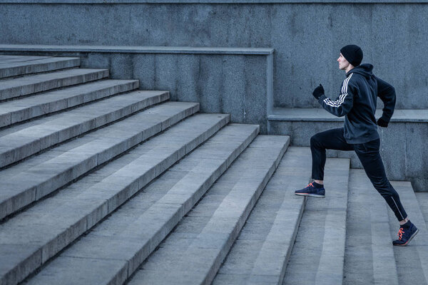 Athletic young man runs up the stairs.