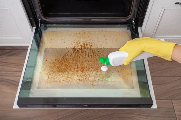 Dirty oven door in the kitchen. Cleaning and tidying.