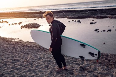 Bir sörfçü bir sörf tahtası ile okyanusun sırtında duruyor.