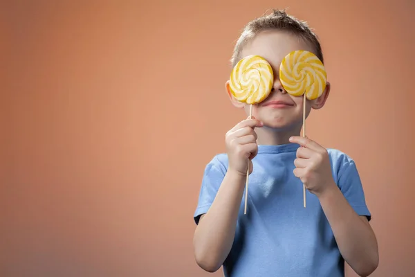 Fröhlicher Gutaussehender Junge Mit Zwei Bonbons Der Hand Kinderfreizeit — Stockfoto