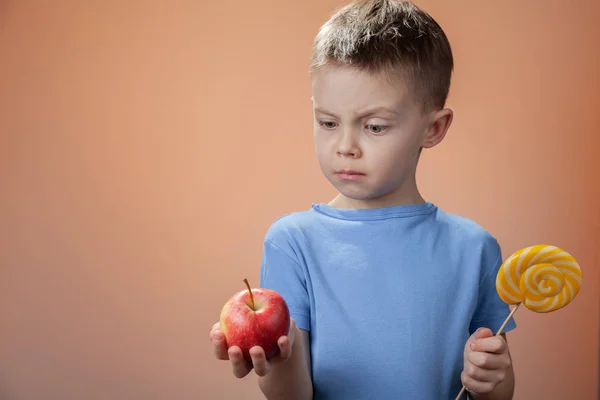 Хлопчик Тримає Цукерки Яблуко Вибирає Вона Хоче Їсти — стокове фото