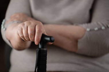 Yaşlı eller bir bakım değnek tutun. Emekli kadın.