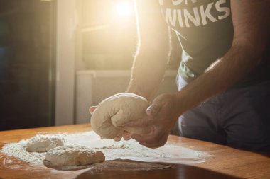 Bir adam unundan yapılmış bir hamur kneads.
