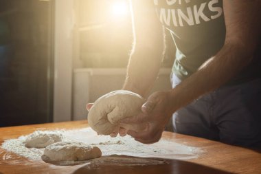 A man kneads a dough made from flour. clipart