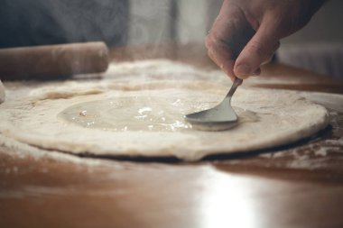 Mutfakta pizza hazırlama ahşap bir masa üzerinde bir adam.